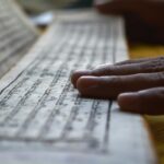 Hands gently rest on Buddhist scripture in Sikkim, reflecting spiritual focus and meditation.
